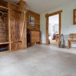 Der Feinsteinzeugplattenboden in Natursteinoptik ist eine ruhige Ergänzung zur Garderobe, Wandtäfelung und Tür aus Naturholz.