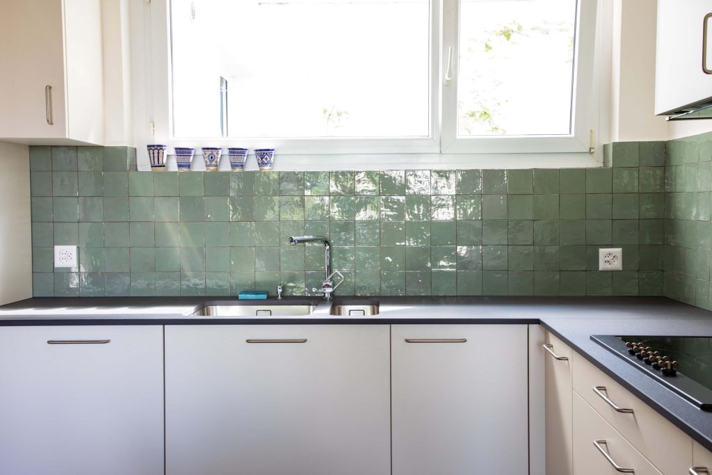 Grüne quadratische Zellige Platten als Küchenrückwand.